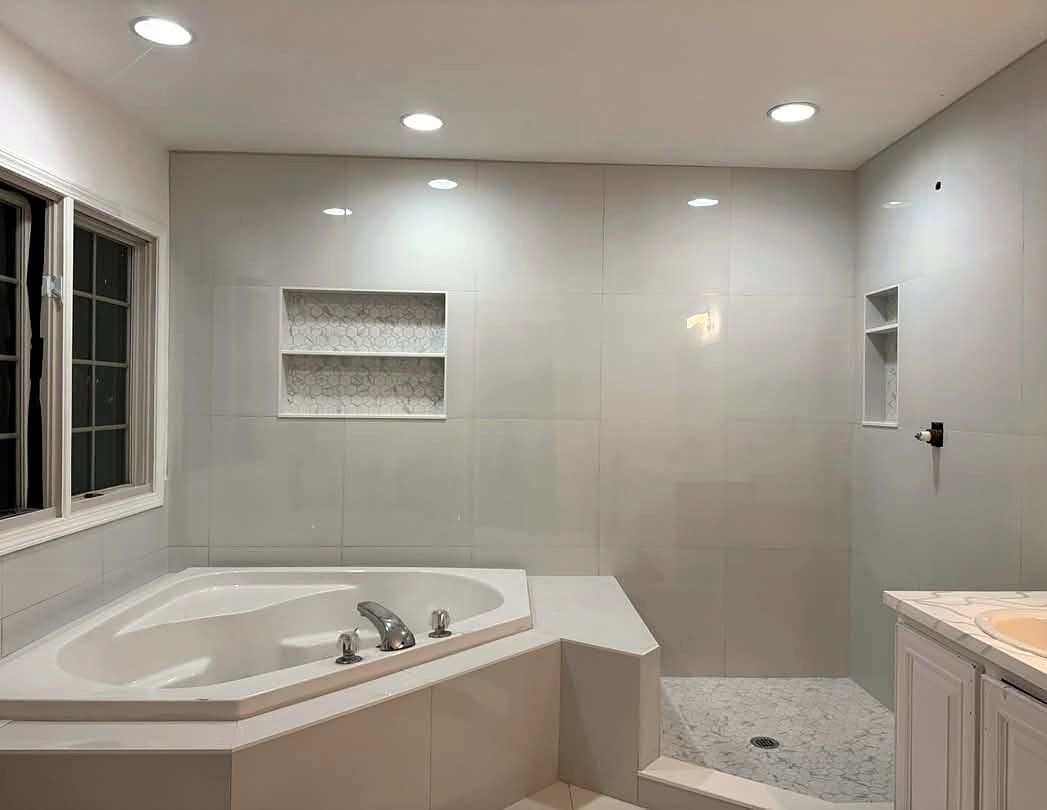 Bathroom with large-format wall tile, tiled niches, corner tub and mosaic shower floor
