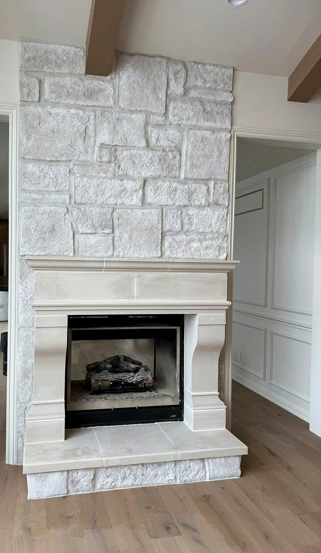 Floor-to-ceiling stone fireplace surround with cast stone mantel and hearth