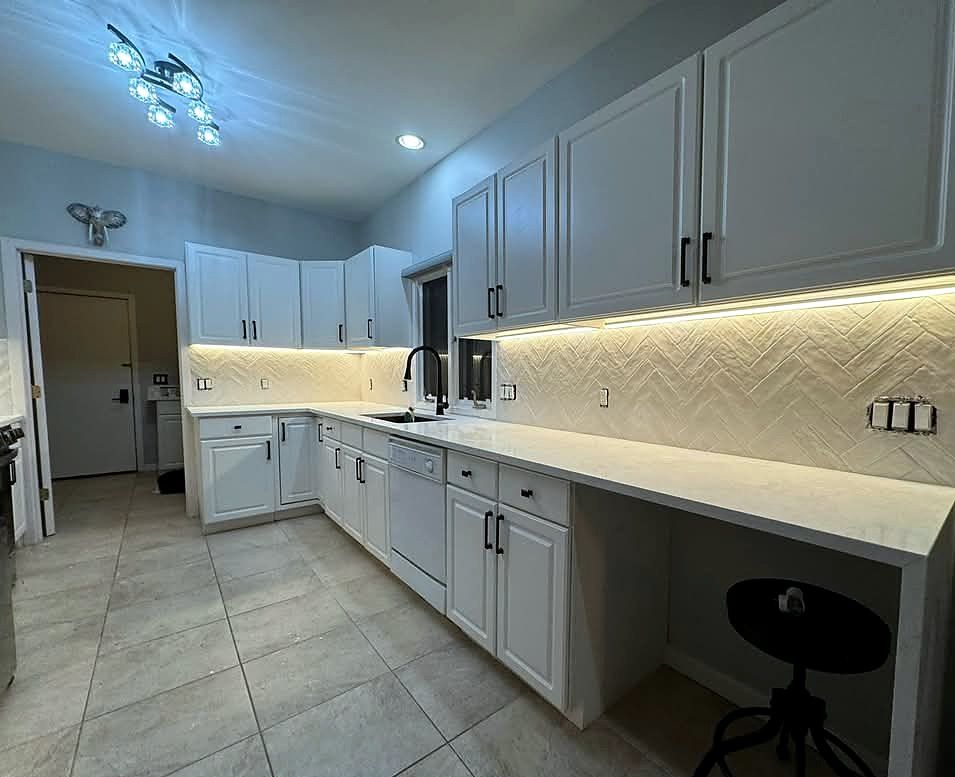 Kitchen with textured herringbone backsplash, under-cabinet lighting and large-format porcelain floor tile