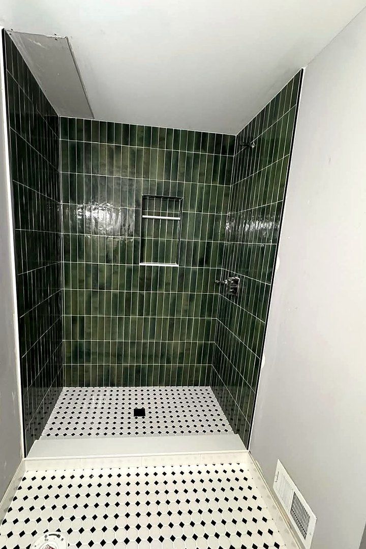 Custom tile shower in dark green vertical stacked tile with black and white octagon mosaic floor